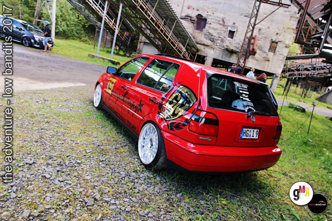 Roter Youngtimer-Kompaktwagen mit Tuning-Ausstattung auf Veranstaltungsgelände im Steinbruch, im Hintergrund weitere Fahrzeuge