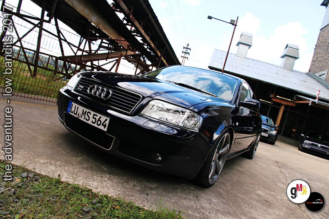 Schwarzer Audi-Youngtimer mit Charakter steht auf dem Gelände einer Veranstaltung mit Industriekulisse