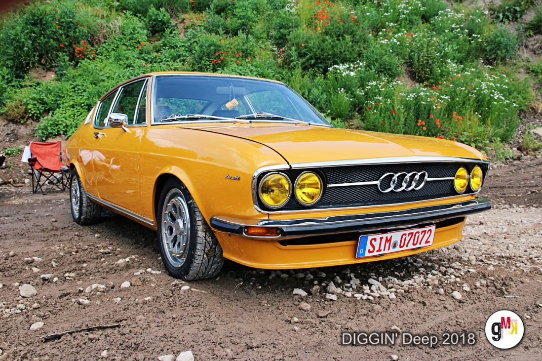 Gelber Audi-Oldtimer mit charakteristischen Doppelscheinwerfern bei der DIGGIN' Deep 2018 Rallye in der Eifel, im Hintergrund grüne Böschung
