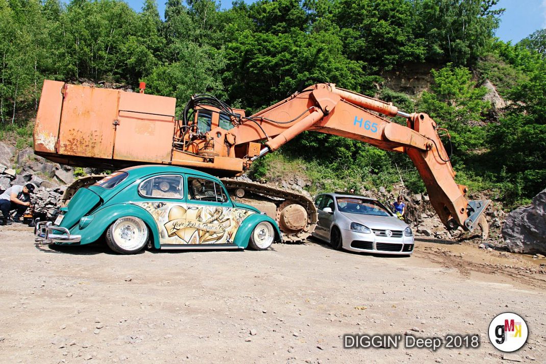 Bagger zerquetscht türkisfarbenen Oldtimer-Käfer und silberne Limousine auf dem Gelände der Veranstaltung DIGGIN' Deep 2018 in der Eifel