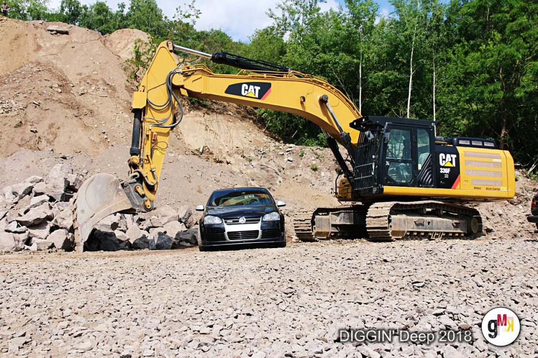 Gelber Bagger zerlegt einen schwarzen VW Golf bei der Automobilzerstörungs-Show DIGGIN' Deep 2018 in der Eifel