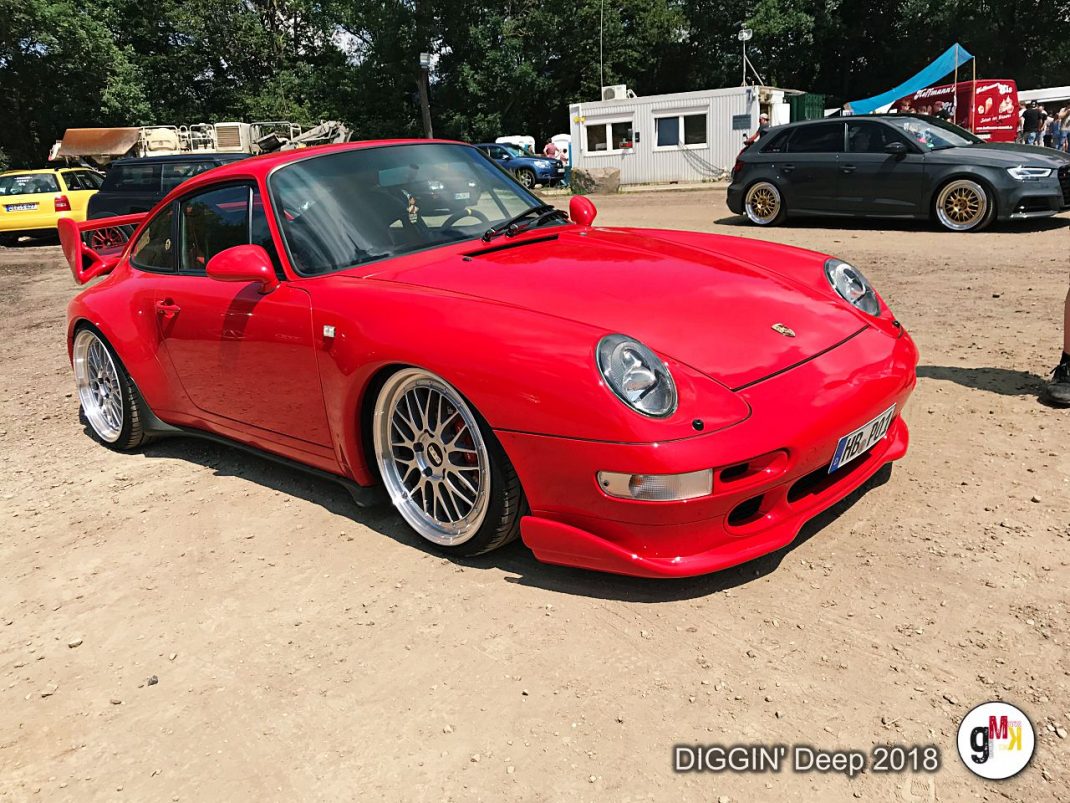 Roter Porsche 911 Turbo 3.6 auf Youngtimer-Treffen mit weiteren Fahrzeugen und Zeltdächer im Hintergrund