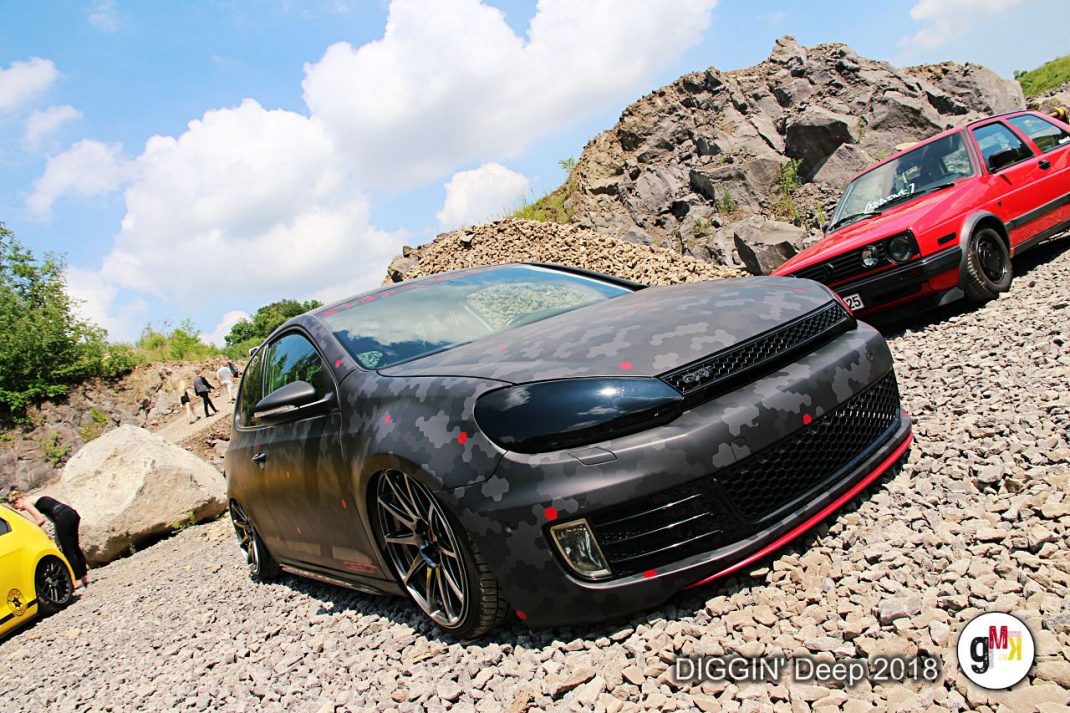 Schwarzer Youngtimer-Kompaktwagen mit roten Akzenten auf Kiesgelände, rotes Fahrzeug im Hintergrund bei der Youngtimer-Tour DIGGIN' Deep 2018 in der Eifel