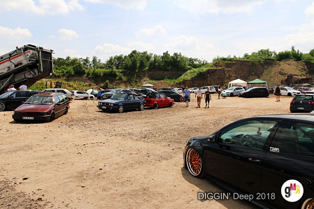 Oldtimer und Youngtimer auf sandiger Freifläche beim Treffen „DIGGIN' Deep 2018" in der Eifel, Teilnehmer zwischen geparkten Fahrzeugen