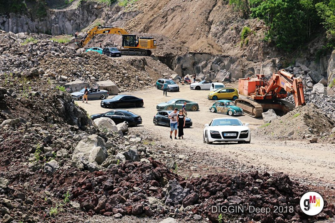Sportwagen und Oldtimer-Fahrzeuge versammelt in einem Steinbruch während der DIGGIN' Deep Veranstaltung in der Eifel, mit Baggern und Teilnehmern