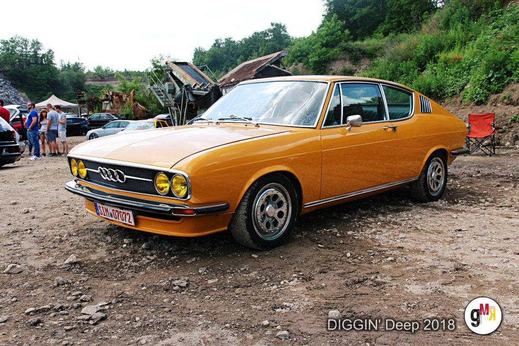 Orangefarbener Audi Oldtimer-Coupé auf Treffen DIGGIN' Deep 2018 in der Eifel, Besucher und weitere Fahrzeuge im Hintergrund