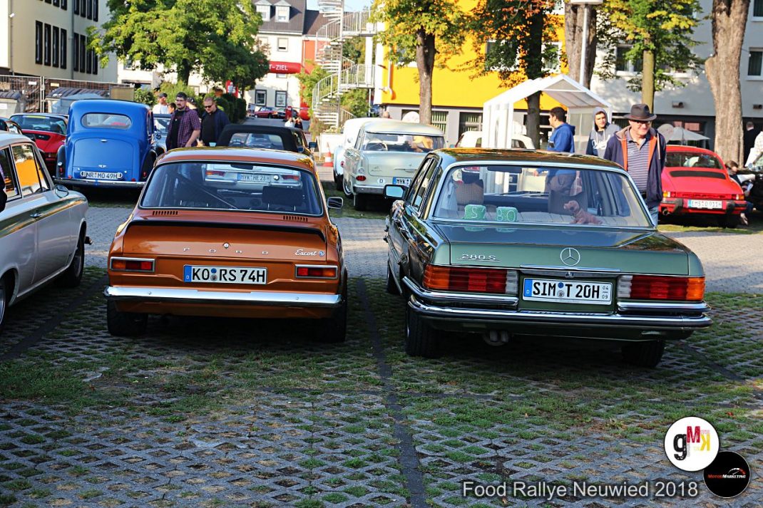 Oldtimer-Limousinen und Cabriolets nebeneinander auf gepflastertem Platz bei der Food Rallye Neuwied mit Besuchern und Bäumen im Hintergrund