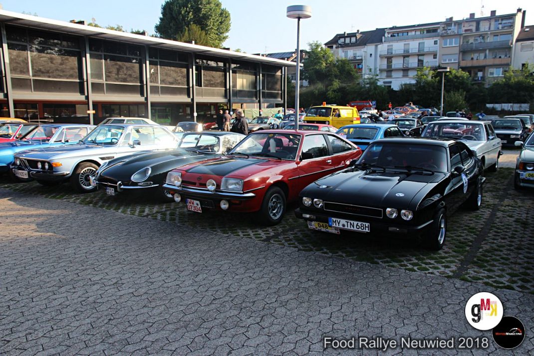 Mehrere Oldtimer-Sportwagen aus verschiedenen Jahrzehnten parken auf einem Platz beim Food-Rallye-Event in Neuwied