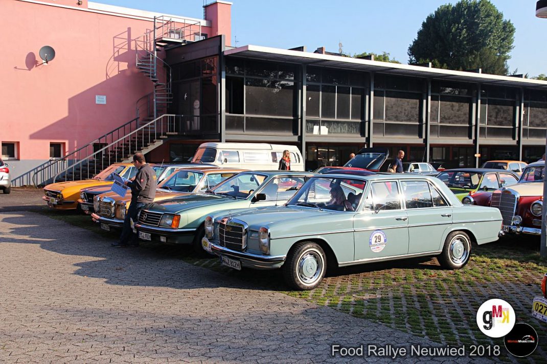 Oldtimer-Fahrzeuge verschiedener Jahrzehnte stehen auf einem Platz vor Industriegebäuden bei der Food Rallye Neuwied 2018