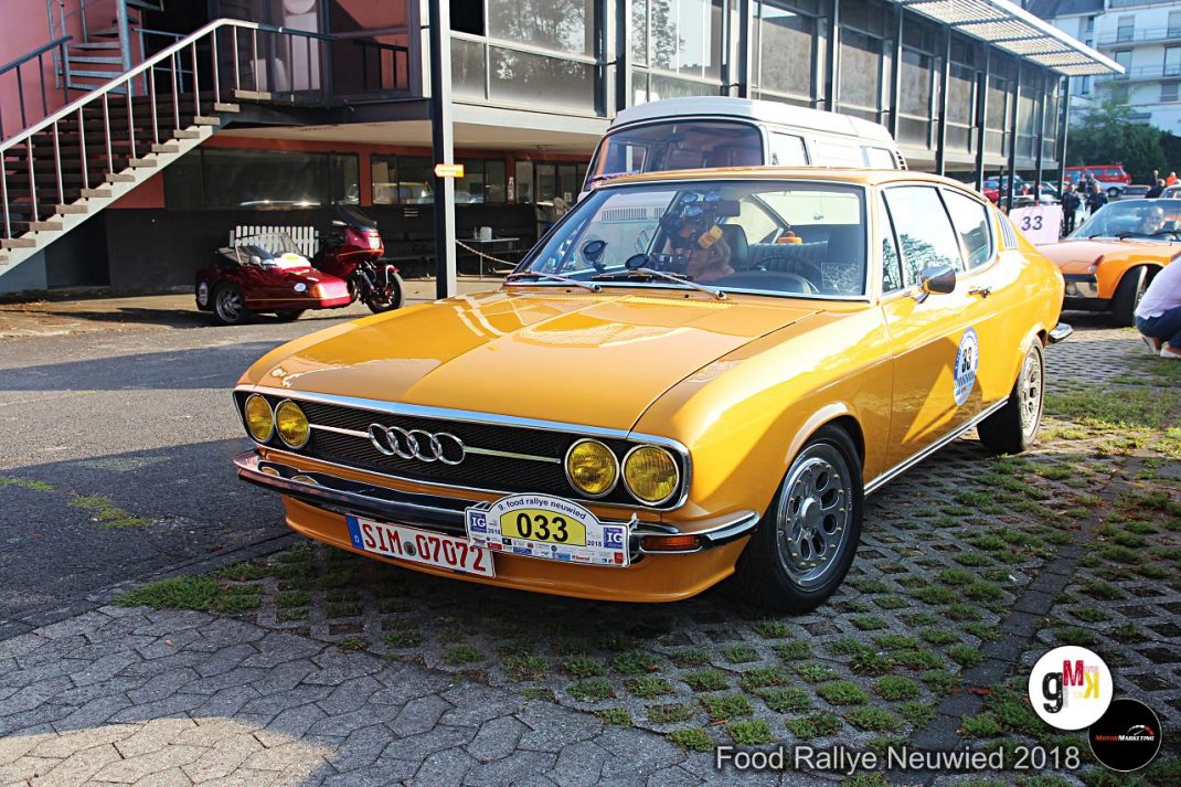 Gelber Audi-Oldtimer mit Startnummer 033 bei der Food Rallye Neuwied 2018, daneben rote Motorräder und weitere Fahrzeuge