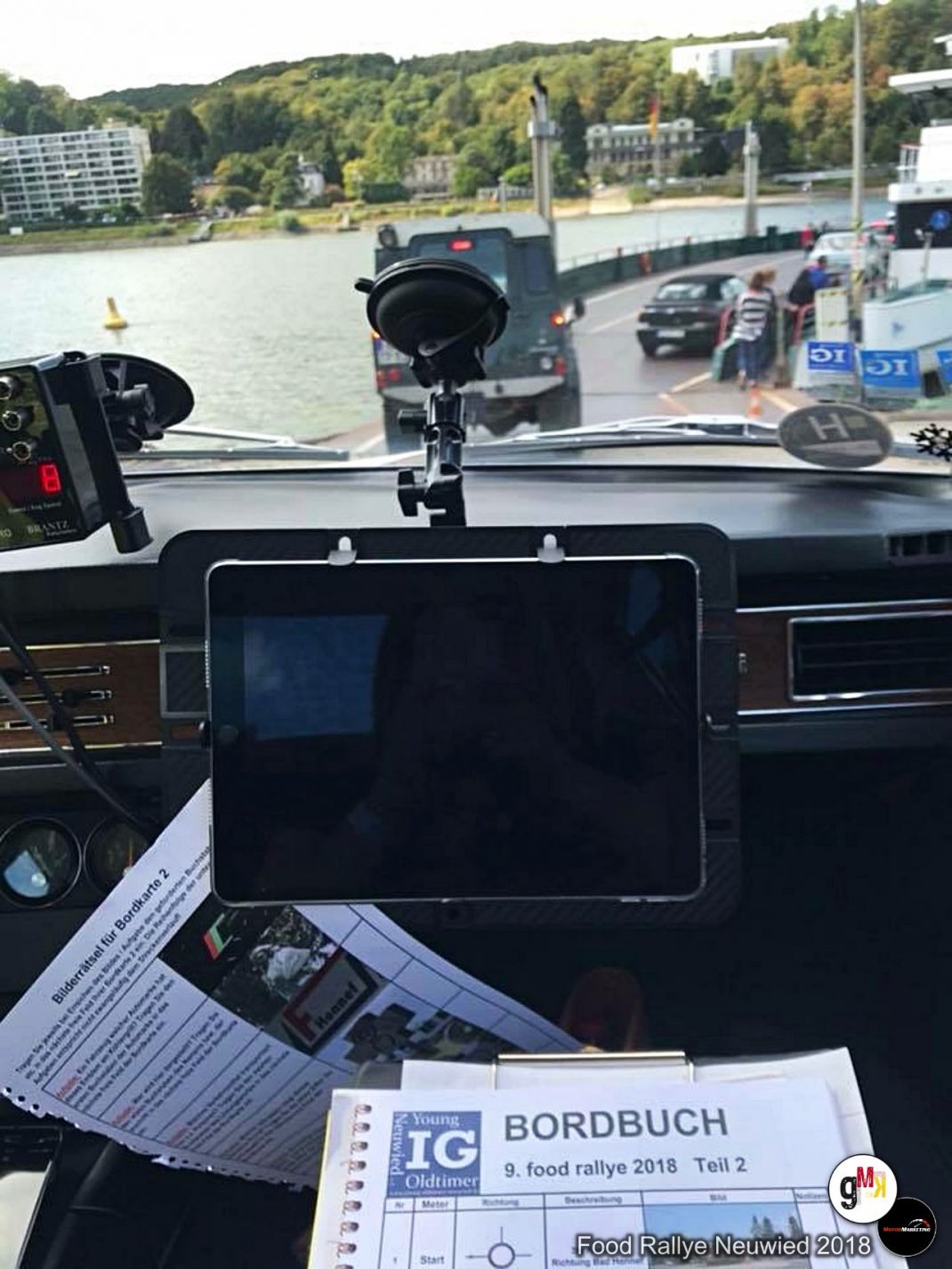 Blick aus Oldtimer-Fahrzeug auf Rallye-Strecke an Flussufern mit Navigationstafel und Bordbuch der Food Rallye Neuwied 2018