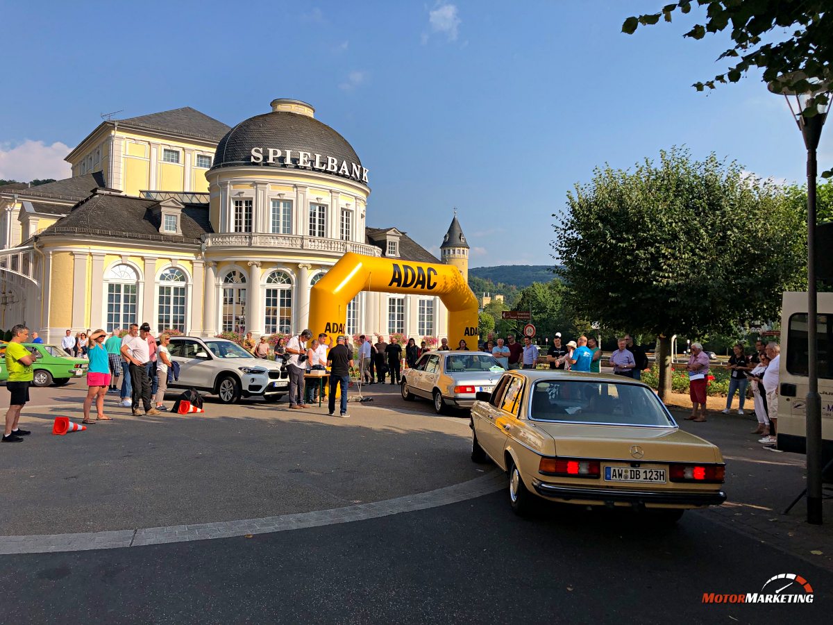 Oldtimer-Limousinen fahren unter gelbem ADAC-Bogen vor historischem Spielbank-Gebäude zur ADAC Mittelrhein Classic 2022