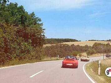 Rotes Oldtimer-Cabrio auf kurviger Landstraße während der ADAC Oldtimerfahrt durch hessisch-thüringische Hügellandschaft