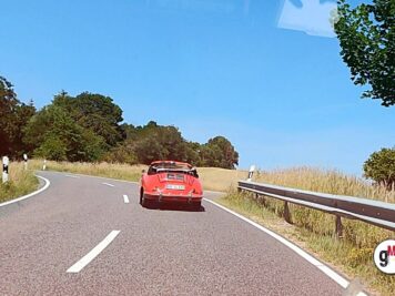 Roter Oldtimer-Cabrio fährt auf kurviger Landstraße während der ADAC Oldtimerfahrt Hessen-Thüringen
