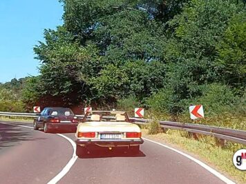 Oldtimer-Limousinen in Rot fahren hintereinander auf kurvenreicher Straße mit Leitplanken und Waldkulisse bei der ADAC Oldtimerfahrt Hessen-Thüringen