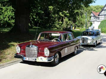 Zwei Oldtimer-Limousinen aus den 1950er Jahren fahren in einer Kolonne bei der ADAC Oldtimerfahrt Hessen-Thüringen, im Hintergrund ein Fachwerkhaus