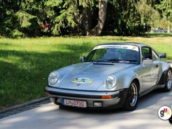 Silberner Porsche 911 Coupé mit Startnummer bei der ADAC Oldtimerfahrt Hessen-Thüringen, parkend an Landstraße mit Baumkulisse