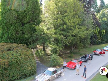 Oldtimer-Fahrzeuge in einer Reihe an Parkplatz neben Baum bewachsenem Bachlauf, Teilnehmer besichtigen die Autos bei der ADAC Oldtimerfahrt Hessen-Thüringen