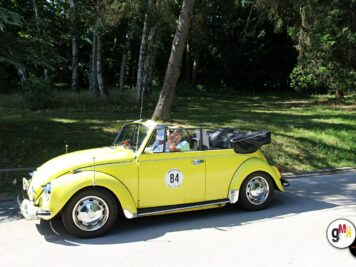 Gelber Oldtimer-Käfer mit Startnummer 84 und offenen Dach fährt durch eine Allee mit Laubbäumen zur ADAC Oldtimerfahrt Hessen-Thüringen