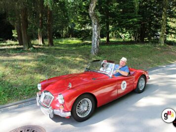 Rotes Oldtimer-Cabrio mit zwei Fahrern auf waldiger Strecke während der ADAC Oldtimerfahrt Hessen-Thüringen