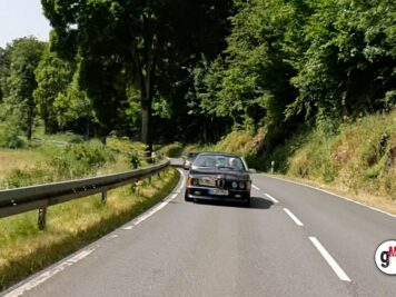BMW 3er Coupé fährt auf kurvenreicher Landstraße durch bewaldete Hügellandschaft bei der ADAC Oldtimerfahrt Hessen-Thüringen