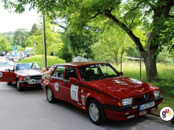 Zwei rote Youngtimer-Limousinen mit Startnummern bei der ADAC Oldtimerfahrt Hessen-Thüringen, parkend unter grünen Bäumen