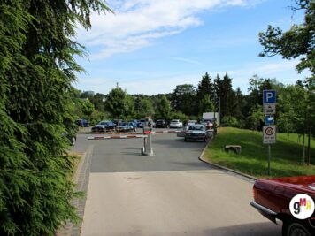 Parkplatz mit verschiedenen Oldtimern und Teilnehmern bei der ADAC Oldtimerfahrt Hessen-Thüringen, umgeben von Grünflächen und Bäumen