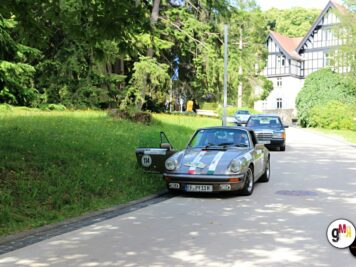 Oldtimer-Sportwagen mit Startnummer fährt auf Landstraße vor Fachwerkhaus bei ADAC Oldtimerfahrt