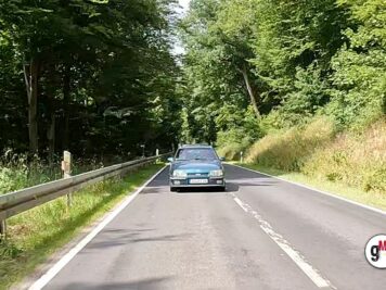 Oldtimer-Limousine fährt auf Landstraße durch grüne Waldlandschaft während der ADAC Oldtimerfahrt Hessen-Thüringen