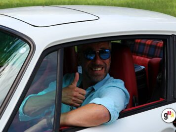 Fahrer in weißem Oldtimer-Cabrio zeigt Daumen hoch aus dem Fenster bei der ADAC Oldtimerfahrt