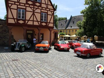 Mehrere Oldtimer-Sportwagen und Limousinen aus den 1950er Jahren vor einem Fachwerkhaus bei der ADAC Oldtimerfahrt Hessen-Thüringen