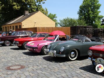Mehrere Oldtimer-Cabrios und Limousinen parken auf Kopfsteinpflaster vor gelbem Fachwerkhaus bei der ADAC Oldtimerfahrt Hessen-Thüringen