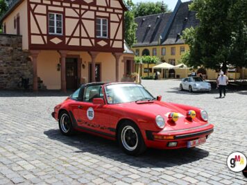 Roter Porsche 911 mit Rallyenummern auf Kopfsteinpflaster vor Fachwerkhaus während ADAC Oldtimerfahrt Hessen-Thüringen