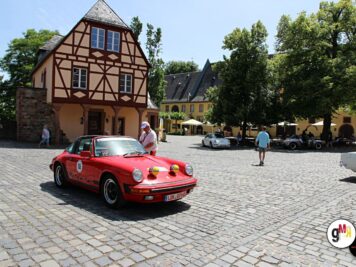 Roter Porsche 911 mit Startnummer auf Marktplatz mit Fachwerkhaus, Teilnehmer einer Oldtimer-Rallye