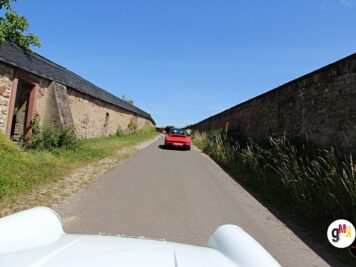 Zwei Oldtimer-Cabriolets fahren auf enger Landstraße zwischen alten Steinmauern während der ADAC Oldtimerfahrt Hessen-Thüringen