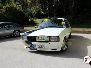 Weißer Oldtimer-Sportwagen mit Startnummer bei der ADAC Oldtimerfahrt Hessen-Thüringen, daneben grauer Oldtimer auf parkplatzähnlichem Gelände mit Bäumen