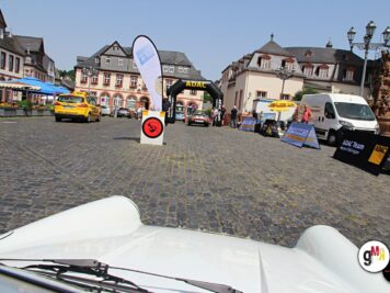 Blick aus einem Oldtimer-Cabrio auf den Marktplatz mit ADAC-Zieltor, gelben Taxis und Teilnehmern der Hessen-Thüringen-Fahrt