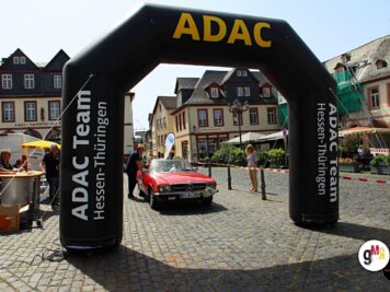 Roter Oldtimer-Sportwagen fährt unter ADAC-Zielportal in Altstadtplatz während Hessen-Thüringen Oldtimerfahrt