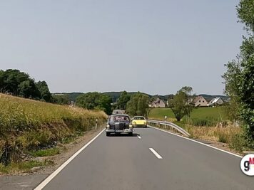 Oldtimer-Cabrio und Youngtimer-Sportwagen fahren auf einer Landstraße durch grüne Hügellandschaft bei der ADAC Oldtimerfahrt Hessen-Thüringen