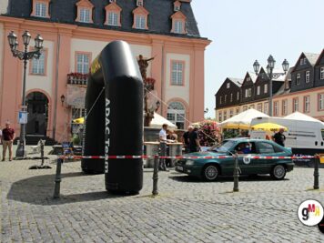 Oldtimer-Limousine neben großer schwarzer Kunststoffskulptur auf historischem Marktplatz mit Fachwerk-Häusern bei ADAC Oldtimerfahrt