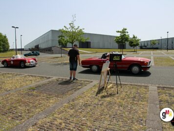 Teilnehmer mit Kamera dokumentiert rote Oldtimer-Cabrios und Limousinen auf Parkplatz bei ADAC Oldtimerfahrt Hessen-Thüringen
