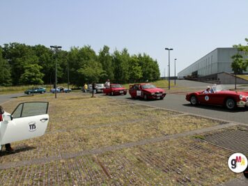 Oldtimer-Fahrzeuge verschiedener Jahrzehnte stehen auf befestigtem Platz bei der ADAC Oldtimerfahrt Hessen-Thüringen, Teilnehmer begutachten die Autos