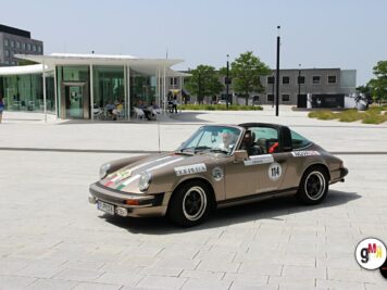 Porsche 911 Targa mit Rallyenummern auf großzügigem Platz vor moderner Architektur bei der ADAC Oldtimerfahrt Hessen-Thüringen