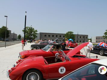 Mehrere rote Oldtimer-Cabrios und Sportwagen auf einem öffentlichen Platz bei der ADAC Oldtimerfahrt Hessen-Thüringen mit geöffneten Motorhauben und Besuchern