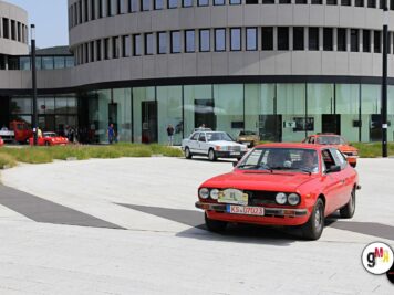 Rote Oldtimer-Limousine fährt auf Platz vor moderner Gebäudearchitektur bei der ADAC Oldtimerfahrt Hessen-Thüringen