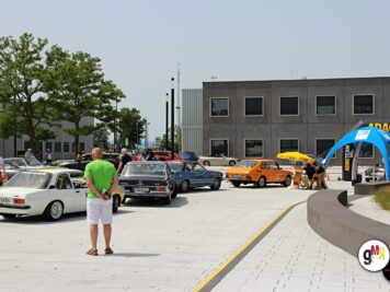 Verschiedene Oldtimer-Fahrzeuge auf einem Parkplatz bei der ADAC Oldtimerfahrt Hessen-Thüringen, mit Teilnehmern und blauem Zeltaufbau