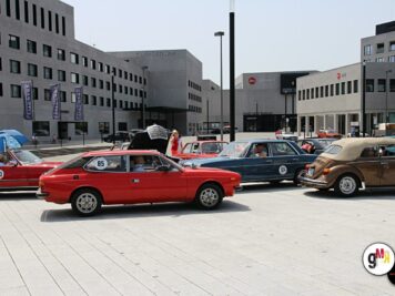 Mehrere Oldtimer-Fahrzeuge starten zur ADAC Oldtimerfahrt Hessen-Thüringen auf einem Platz vor modernen Gebäuden