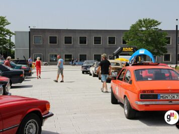 Oldtimer und Youngtimer verschiedener Jahrzehnte auf großem Parkplatz mit Besuchern bei der ADAC Oldtimerfahrt Hessen-Thüringen