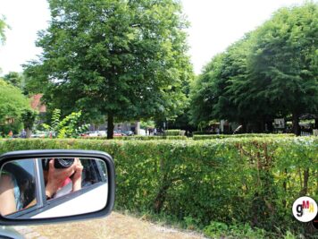 Fahrergesicht im Seitenspiegel eines Oldtimers während der ADAC Oldtimerfahrt Hessen-Thüringen, Parkplatz mit Hecken und Bäumen im Hintergrund