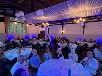 Festsaal mit Gästen an Banketttischen zur ADAC Oldtimerfahrt Hessen-Thüringen, blaue Beleuchtung und Dekoration